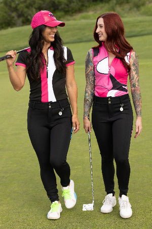 Two women in matching NGA pink and black golf outfits on a golf course.