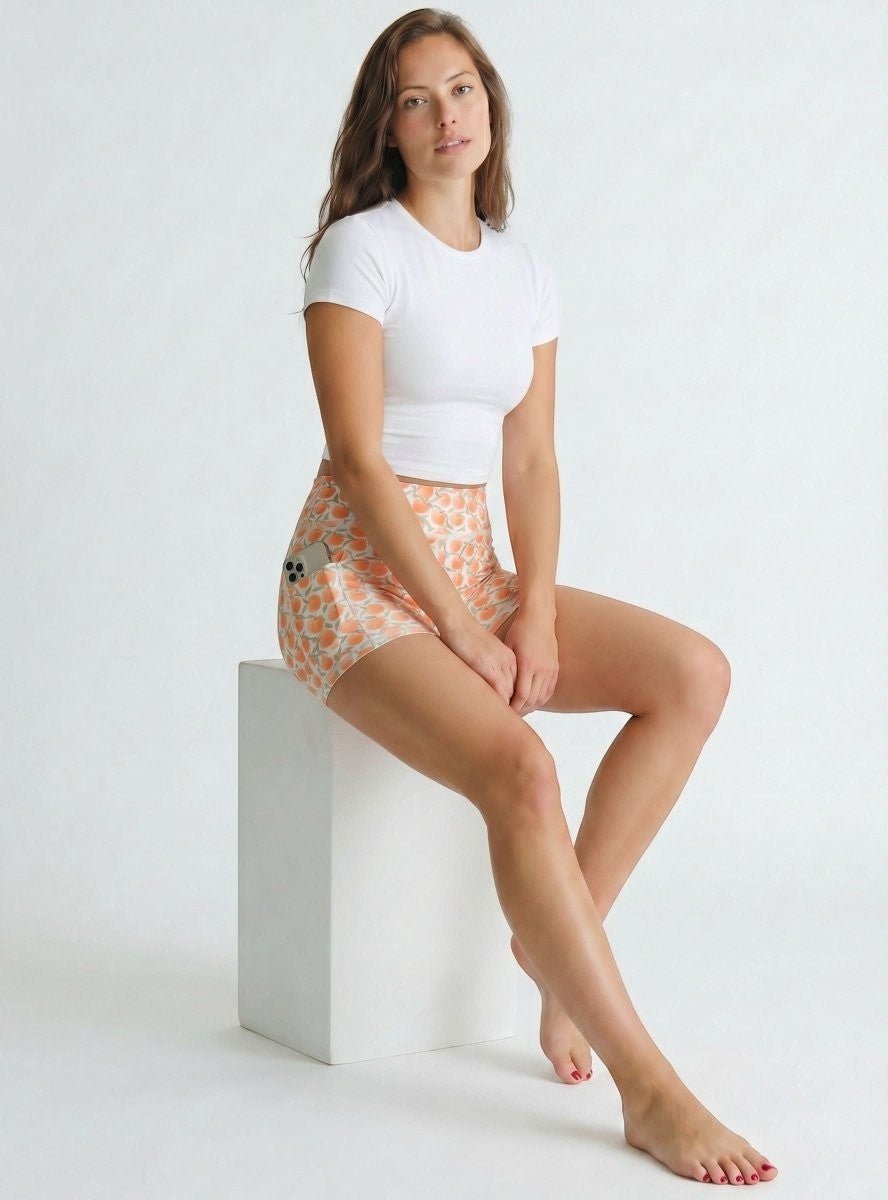 NGA - No Girls Allowed Luxe Unders compression shorts in peach print with side pocket, worn by a woman on a white block.